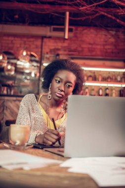 Parlak genç Afrikalı kız concernedly dizüstü bilgisayar ekranına bakarak