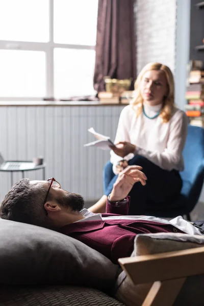 Hombre barbudo visitando terapeuta acostado en un sofá que necesita un poco de relajación — Foto de Stock