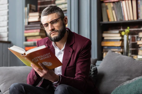 Homem sentindo pensativo ao ler livro sobre astrologia do dinheiro — Fotografia de Stock