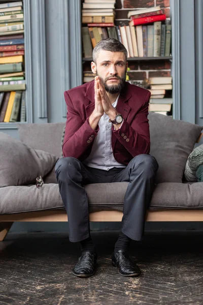 Bello uomo d'affari elegante con giacca rosso scuro seduto sul divano — Foto Stock