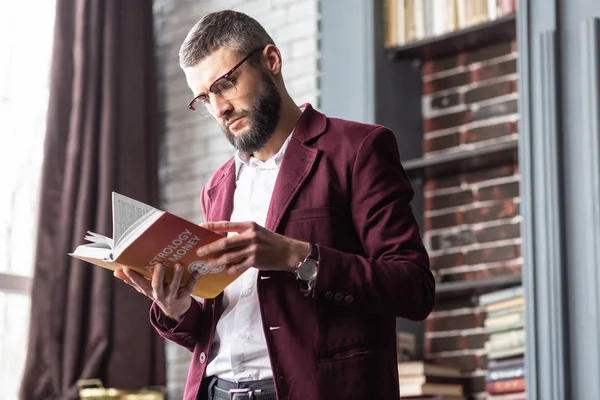 Businessman feeling interested reading book about astrology and money — Stock Photo, Image