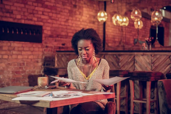 Nice-looking Afro-Amerikaanse ontwerper angstig te kijken naar tekeningen aan café tafel — Stockfoto