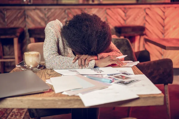 Уставшая женщина, к сожалению, опираясь на стол, покрытый дизайнерскими рисунками — стоковое фото
