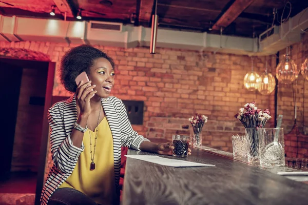 Heldere aantrekkelijke Afro-Amerikaanse young-adult meisje spreken op telefoon in bar — Stockfoto