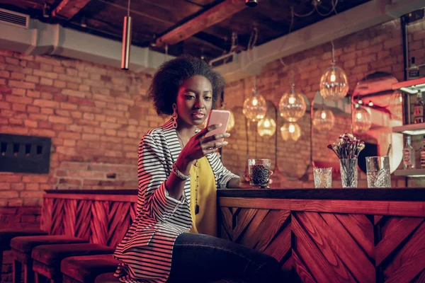 Chica seductora con un abrigo elegante mirando el teléfono en las manos . — Foto de Stock