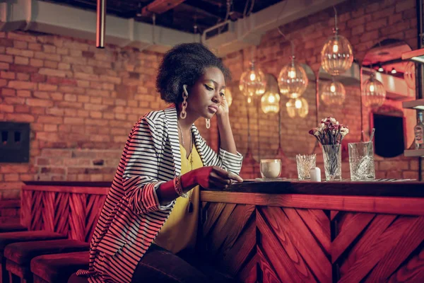 Stijlvolle Afro-Amerikaanse vrouw zitten met koffie kijken naar menu — Stockfoto