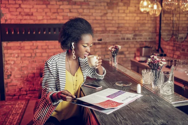Elegante Afro-Amerikaanse vrouw koffie drinken en spiegelen modeblad — Stockfoto