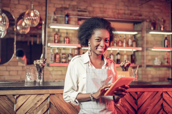 Happy bar worker holding tablet in hands during work process
