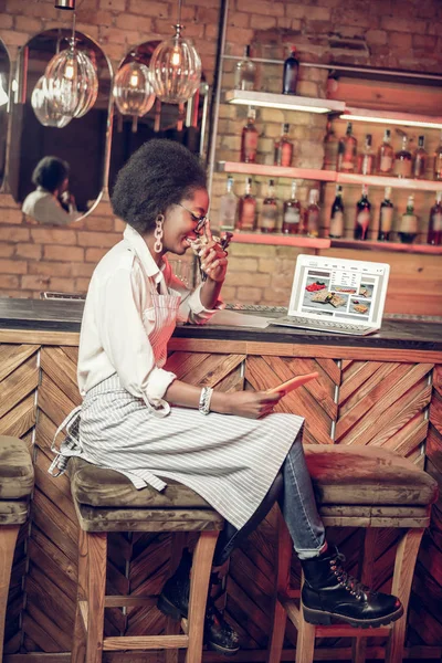 Афроамериканская официантка, сидящая в кресле возле барной стойки — стоковое фото