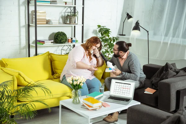 Upset overweight female person crying during consultation