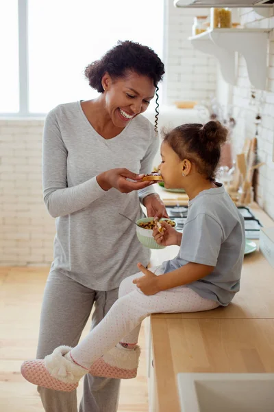 Positiv glad internationella kvinnliga person utfodring hennes kid — Stockfoto