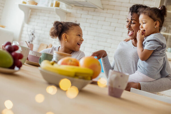 Delighted curly-haired woman spending morning with her kids