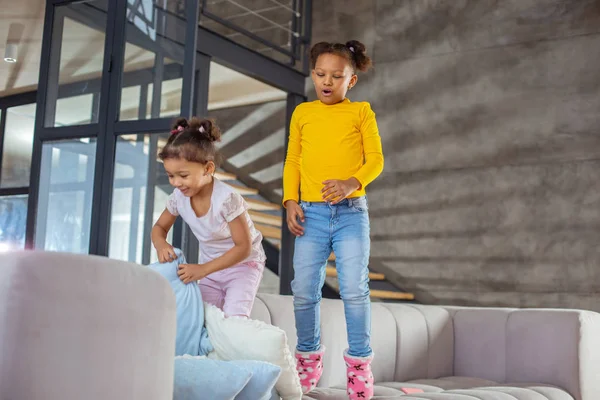 Freudig lockiges brünettes Kind springt auf Sofa — Stockfoto