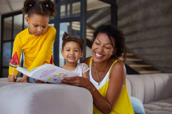 Positiva mujer encantada leyendo libro a sus hijos — Foto de Stock