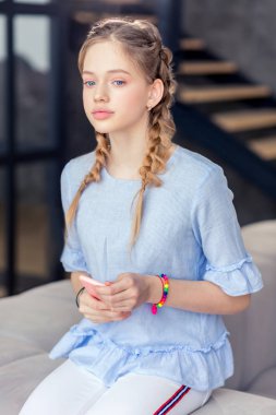 Sevimli uzun saçlı sarışın kız koltukta oturan