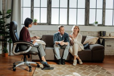 Terapist ile randevu sırasında kanepede oturup sakin orta yaş kaç