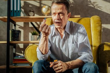 Kapsayıcıdan hapları hoş olmayan kısa saçlı yaşlı adam