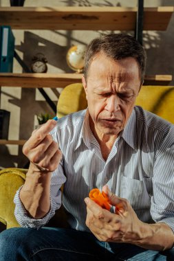 Çizgili gömlekli hap adını gözlemleyerek kısa saçlı yaşlı adam