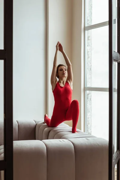 Mujer pacífica y atractiva de pie sobre sus rodillas mientras hace yoga —  Fotos de Stock