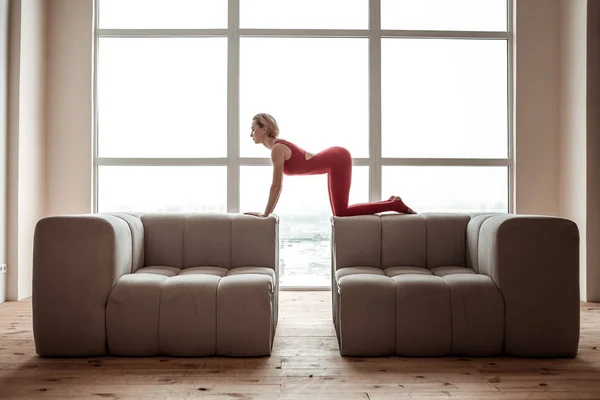 Well-shaped skinny girl with blonde hair sitting on all forth