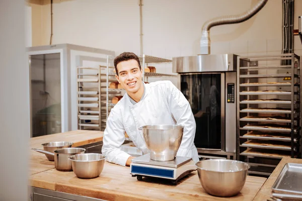 Boulanger aux cheveux bruns pesant de la farine pour de futures pâtisseries — Photo