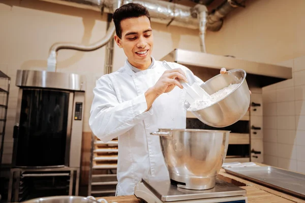 Aangename baker glimlachen tijdens het koken van brood in de keuken — Stockfoto