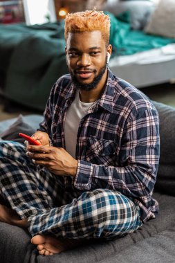 Onun smartphone ile oturan neşeli güzel adam