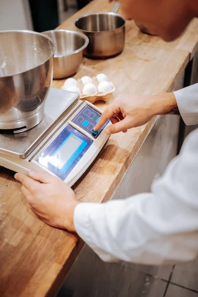 Baker med köksvåg samtidigt väger vispad vita — Stockfoto