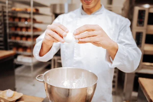 Gros plan du boulanger professionnel brisant l'oeuf dans le bol — Photo