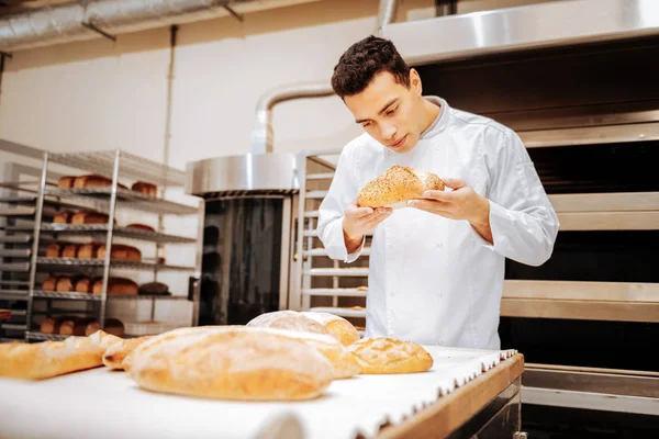 Baker de pé perto da mesa verificando a qualidade do pão — Fotografia de Stock