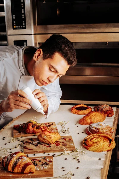 Pâtissier aux cheveux foncés décorant des desserts pâtissiers pour sa classe de maître — Photo