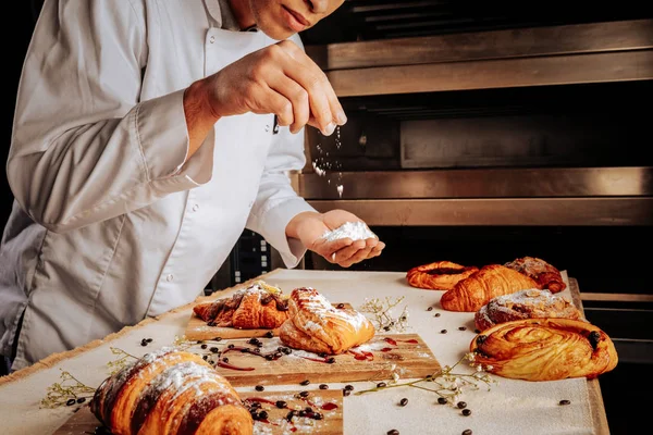 Bagare står nära ugnen och dekorera bakverk desserter — Stockfoto