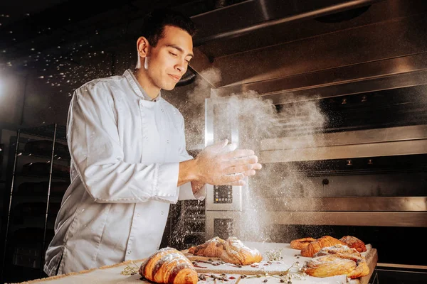 Baker clapping his hands and spilling sugar powder on pastry — Stock Photo, Image