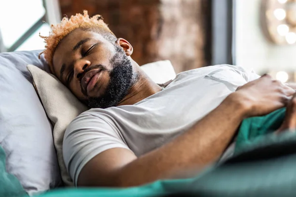 Knappe African American man die liggend op zijn bed — Stockfoto