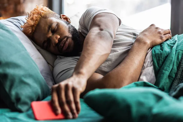 Bonito homem sonolento bonito levando seu smartphone — Fotografia de Stock