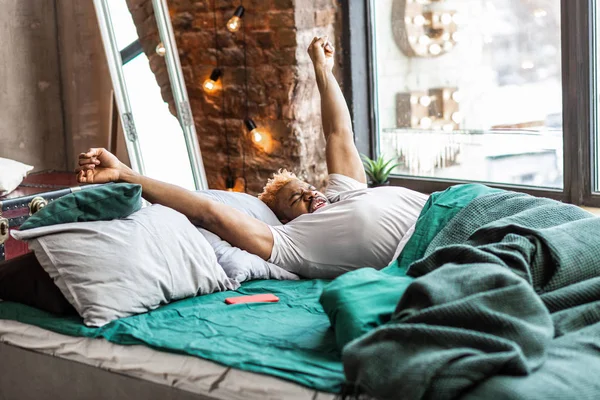 Aardige gezellige man uitrekken zelf in bed — Stockfoto