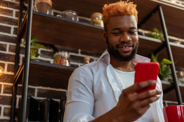 Hombre afroamericano positivo sosteniendo su teléfono inteligente — Foto de Stock