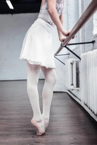 Nice slim young woman touching the barre