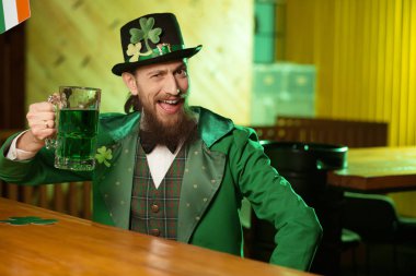 Koyu renk saçlı sakallı genç adam cüce şapkası yeşil bira içmek