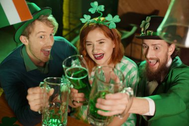 Kızıl saçlı güzel kız bir yeşil kareli gömlek ve erkek gözlük yeşil bira ile yetiştirme st.patricks gün kostümleri