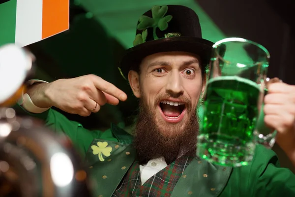 Dark-haired bearded young man in a leprechaun costume feeling good