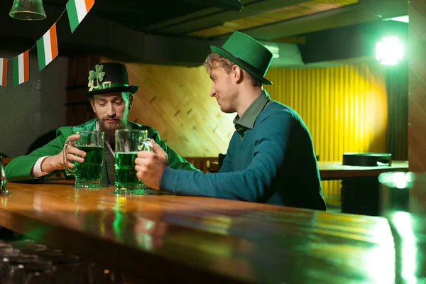 Jeune homme barbu aux cheveux bruns dans un chapeau de lutin et son ami passer la soirée dans le pub — Photo