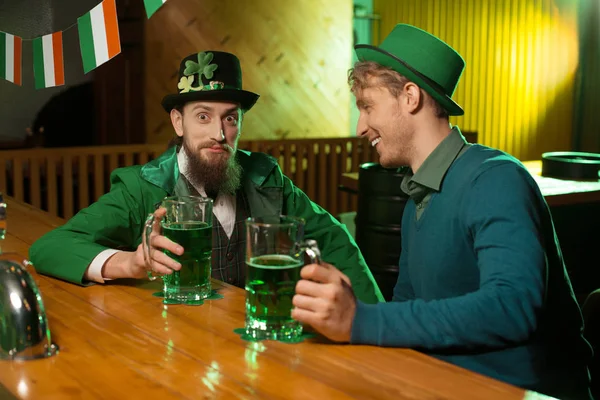 Bruno barbuto giovane uomo in un cappello leprecauno e il suo amico avendo grande momento nel pub — Foto Stock