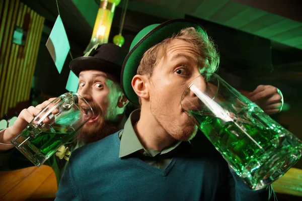 Jovem de cabelos lisos com um chapéu verde e seu amigo barbudo se divertindo — Fotografia de Stock