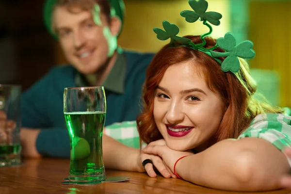 Chica guapa pelirroja con trébol en la cabeza sentada en el mostrador del bar — Foto de Stock