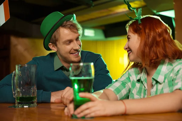 Chica bonita pelirroja con una camisa verde a cuadros y un hombre con un sombrero verde mirándose el uno al otro — Foto de Stock