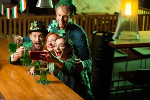 Compañía de buenos amigos en trajes de día st.patricks haciendo selfie —  Fotos de Stock