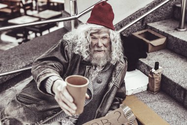 Yalnız dilenci yayalar kağıt bardak ile para için yalvarıyor.