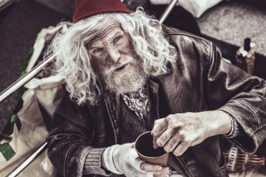 Yaşlı dilenci yabancı para koymak için gösterilen.