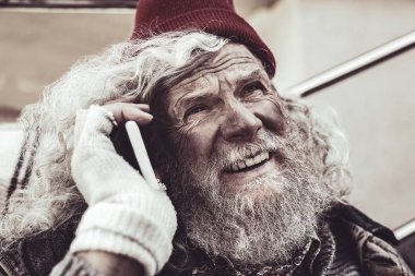 Smartphone üzerinde konuşmak ve gökyüzüne bakarak evsiz bir adam portresi.